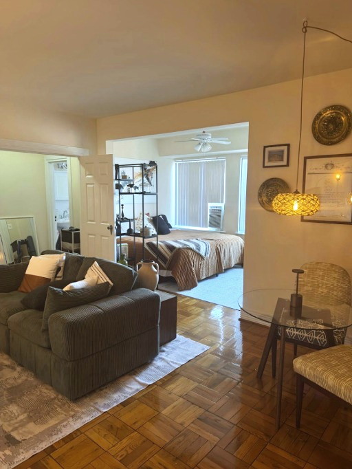 Laura and Nau's home — a warm living room with parquet floors, a green sofa and a bedroom beyond